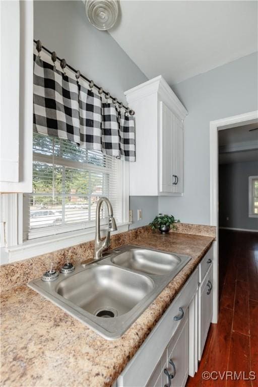 kitchen featuring a sink, white cabinetry, dark wood finished floors, and lofted ceiling