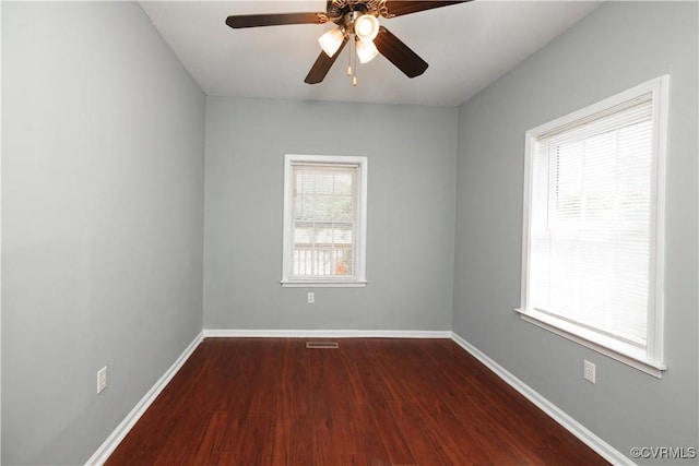 empty room with dark wood-style floors, baseboards, and ceiling fan