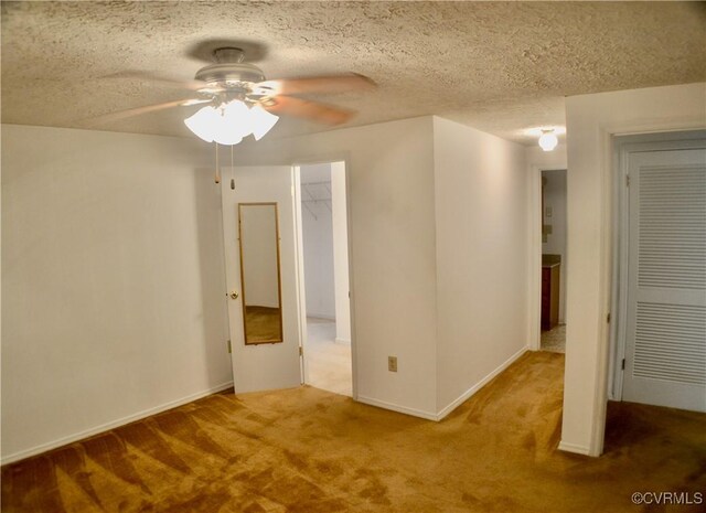 spare room with a textured ceiling, baseboards, ceiling fan, and carpet floors