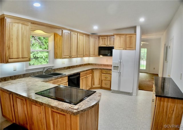 kitchen with a sink, a peninsula, black appliances, recessed lighting, and stone counters