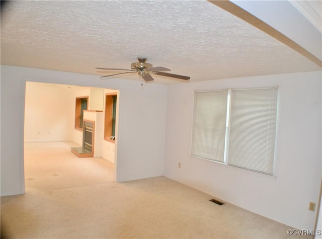 unfurnished room featuring a ceiling fan, carpet flooring, visible vents, and a textured ceiling