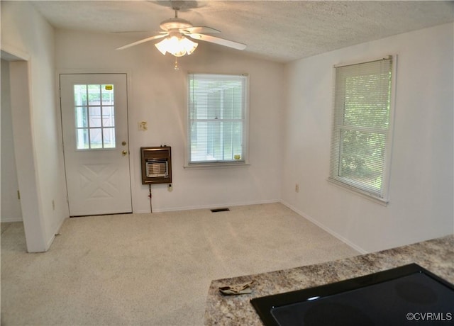 foyer entrance with a ceiling fan, heating unit, a textured ceiling, visible vents, and carpet floors