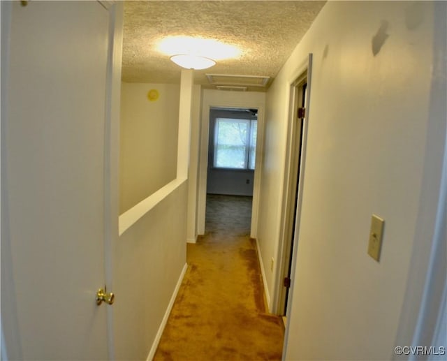 hall featuring light carpet, a textured ceiling, and baseboards