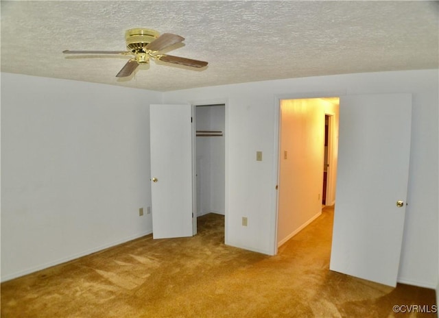 unfurnished bedroom featuring carpet, a closet, a textured ceiling, ceiling fan, and a spacious closet