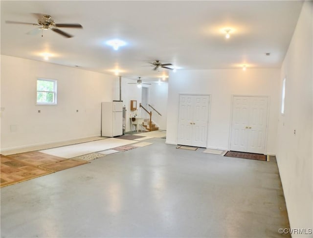 basement featuring stairway, freestanding refrigerator, and a ceiling fan