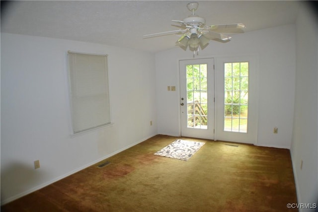spare room featuring carpet, visible vents, baseboards, and ceiling fan