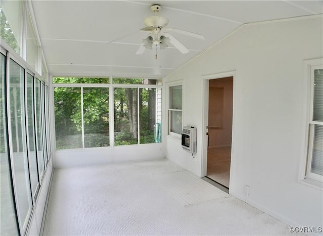 unfurnished sunroom featuring lofted ceiling, heating unit, carpet floors, and a ceiling fan