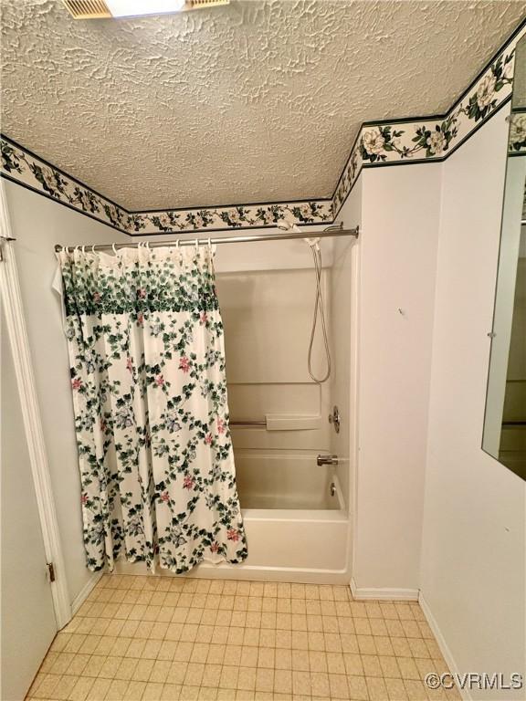 bathroom with baseboards, shower / bathtub combination with curtain, and a textured ceiling