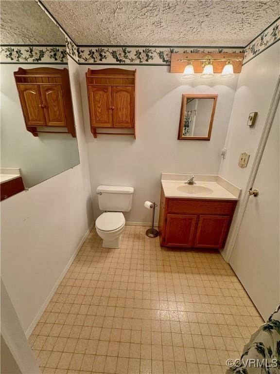 bathroom with toilet, vanity, and baseboards