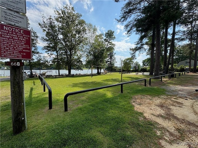surrounding community with a water view and a lawn