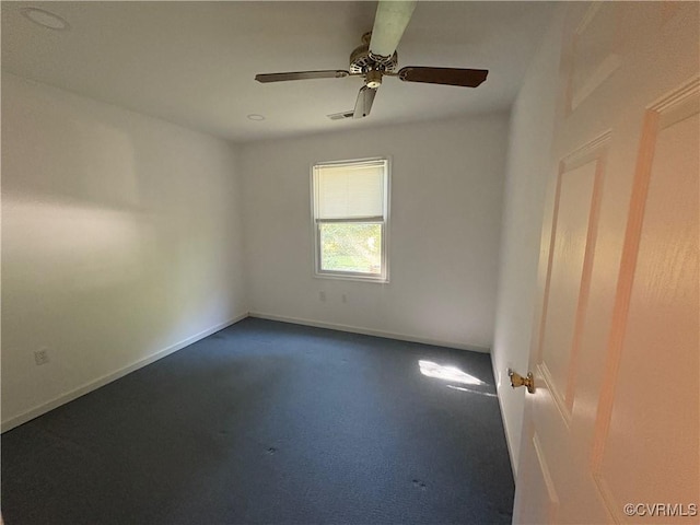 unfurnished room featuring a ceiling fan, dark colored carpet, and baseboards