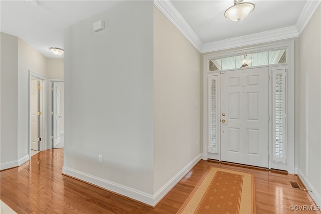 foyer with light wood-style floors, crown molding, and baseboards