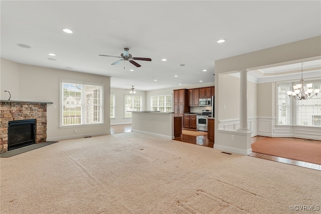 unfurnished living room with carpet floors, recessed lighting, a fireplace, a chandelier, and decorative columns