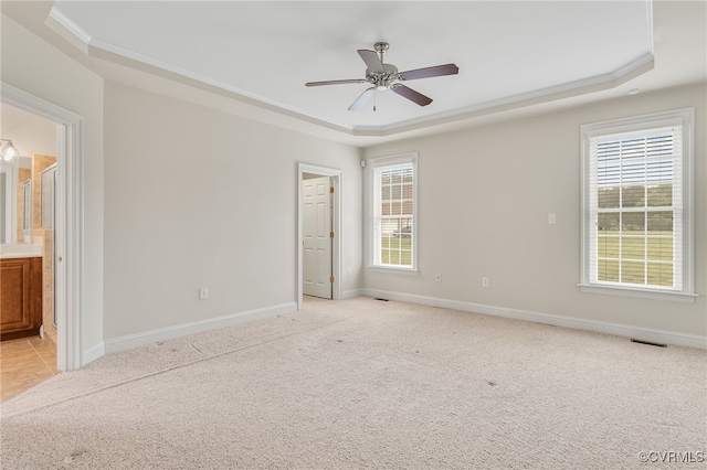 unfurnished bedroom featuring a raised ceiling, light carpet, baseboards, and ornamental molding