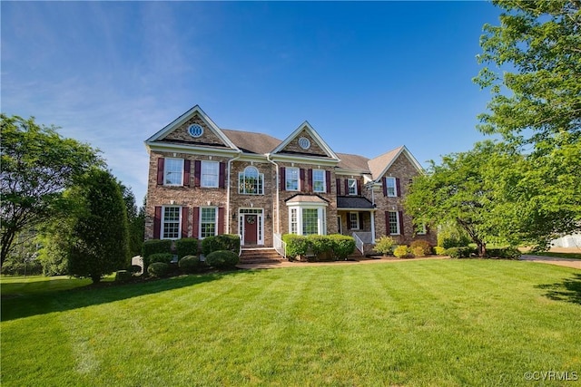 colonial house with a front lawn and brick siding