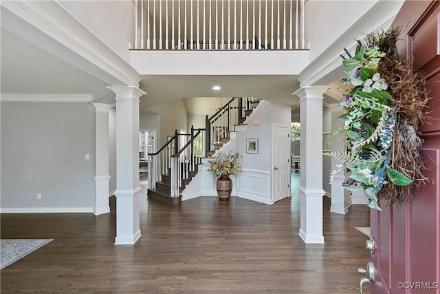 entrance foyer with stairs, a towering ceiling, wood finished floors, and baseboards