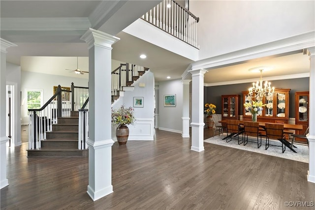 entryway with stairway, ceiling fan, dark wood finished floors, decorative columns, and ornamental molding