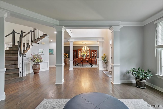 entrance foyer with ornamental molding, wood finished floors, stairway, a chandelier, and ornate columns