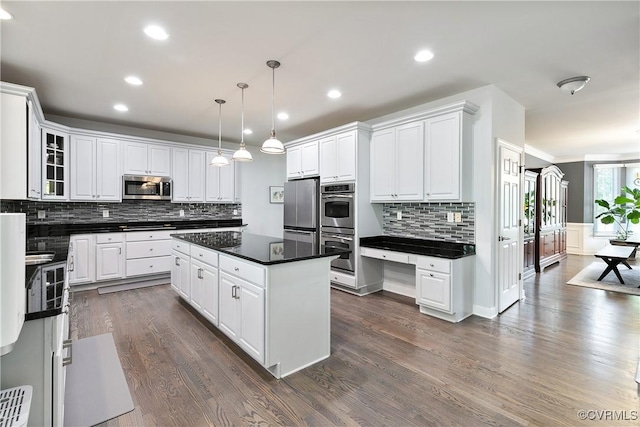 kitchen featuring appliances with stainless steel finishes, dark countertops, a center island, white cabinets, and recessed lighting