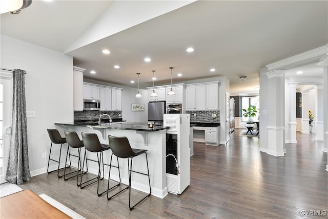 kitchen featuring stainless steel appliances, a peninsula, tasteful backsplash, decorative columns, and recessed lighting