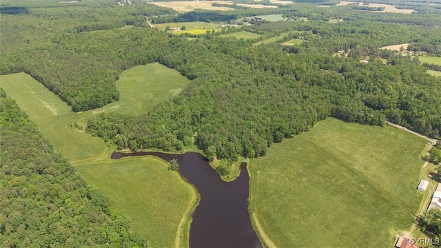 view of property location with a nearby body of water and a forest