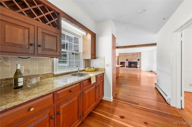 33356 Richmond Tpke, Hanover, VA 23069 - kitchen with a baseboard heating unit, light wood-style floors, tasteful backsplash, a fireplace, and light stone counters