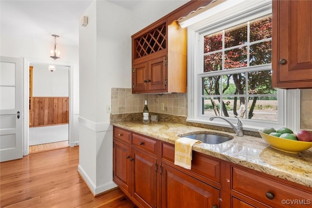 33356 Richmond Tpke, Hanover, VA 23069 - kitchen with a sink, light wood-style flooring, decorative backsplash, light stone counters, and brown cabinets