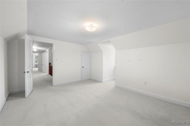 bonus room featuring vaulted ceiling, light carpet, and baseboards