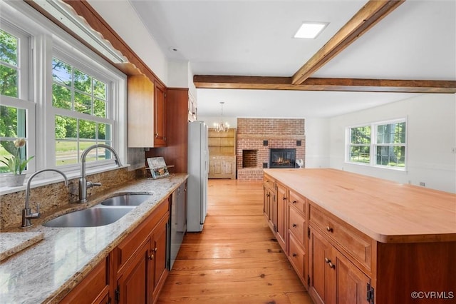 kitchen with a sink, freestanding refrigerator, light wood-type flooring, beamed ceiling, and a chandelier
