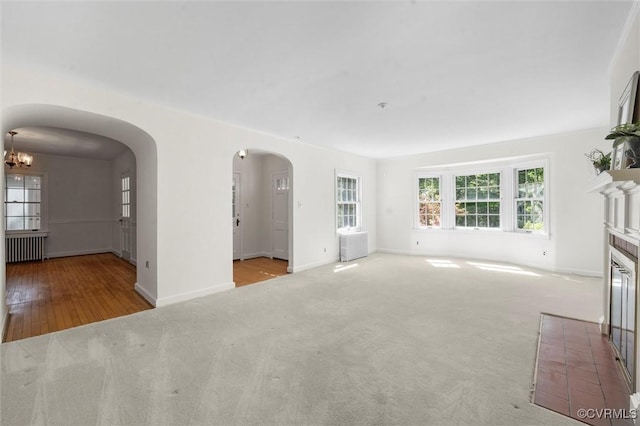 33356 Richmond Tpke, Hanover, VA 23069 - unfurnished living room featuring radiator, arched walkways, carpet flooring, a chandelier, and a fireplace