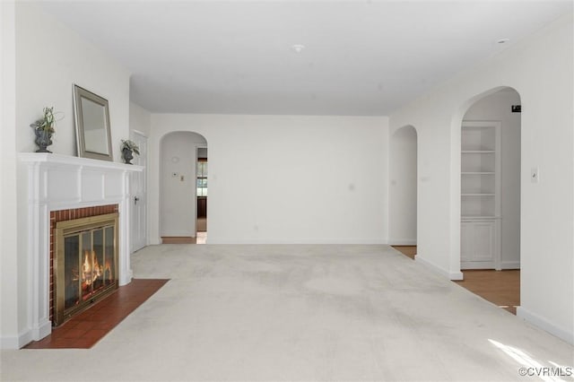 33356 Richmond Tpke, Hanover, VA 23069 - unfurnished living room with carpet flooring, a brick fireplace, built in shelves, baseboards, and arched walkways