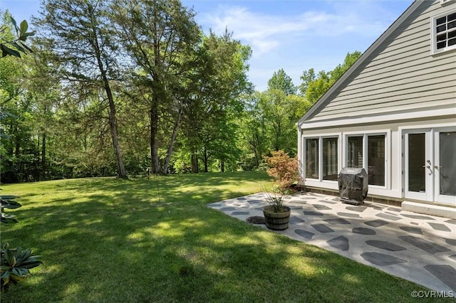 view of green lawn with a patio area and french doors