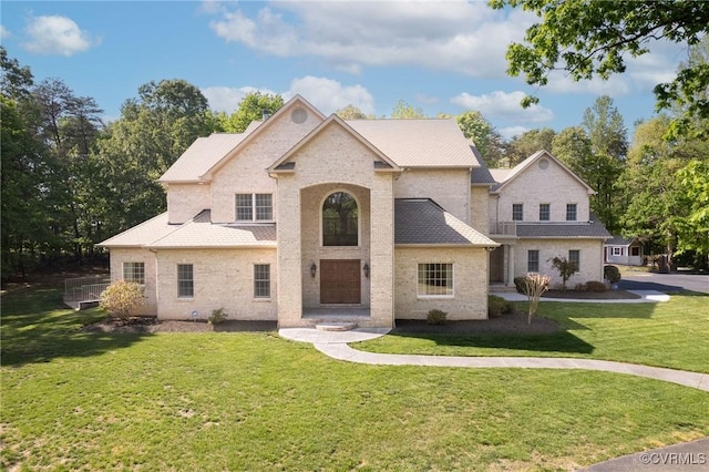french country style house featuring brick siding and a front yard