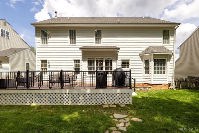 rear view of house with a wooden deck, a shingled roof, and a lawn