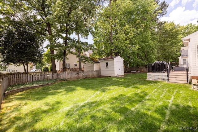 view of yard featuring an outbuilding, a wooden deck, a fenced backyard, and a storage unit