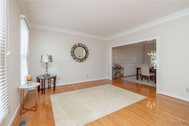 sitting room with a notable chandelier, baseboards, ornamental molding, visible vents, and light wood-type flooring