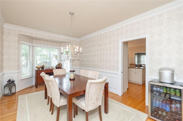 dining space with wallpapered walls, light wood-style floors, and wainscoting