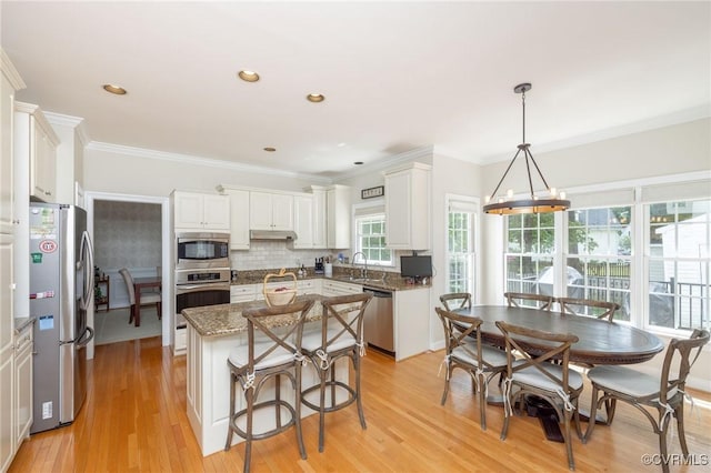 kitchen featuring a center island, tasteful backsplash, a sink, white cabinets, and appliances with stainless steel finishes