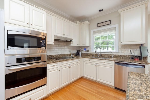 kitchen featuring under cabinet range hood, white cabinetry, appliances with stainless steel finishes, and a sink