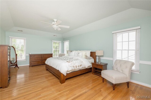 bedroom with multiple windows, light wood finished floors, visible vents, and vaulted ceiling