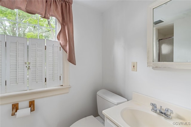 bathroom featuring toilet, a shower with door, and vanity