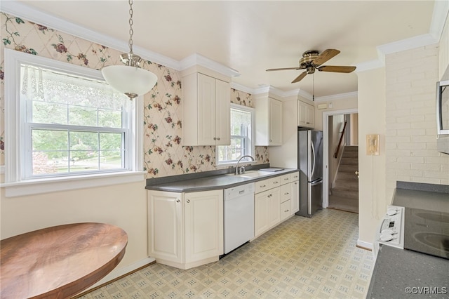kitchen featuring dishwasher, freestanding refrigerator, dark countertops, a sink, and light flooring
