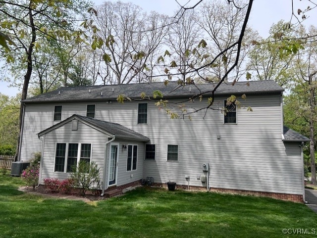 rear view of property with central air condition unit and a yard