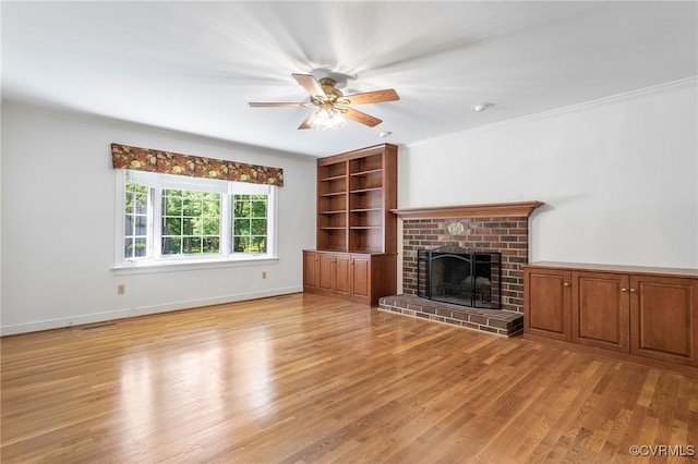 unfurnished living room with light wood finished floors, a fireplace, ornamental molding, a ceiling fan, and baseboards