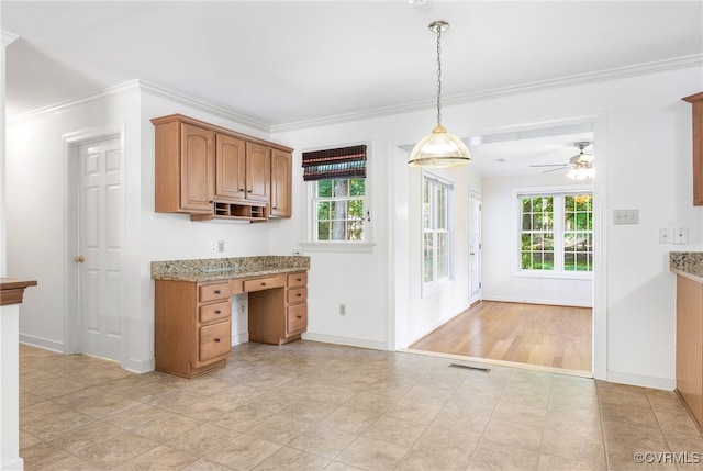 kitchen featuring ceiling fan, baseboards, ornamental molding, light stone counters, and hanging light fixtures