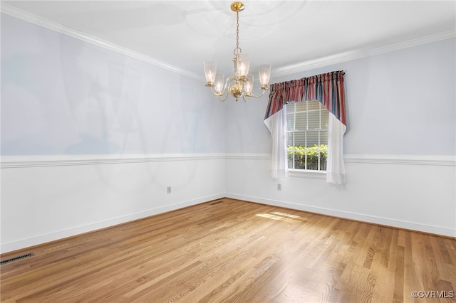 unfurnished room with a chandelier, wood finished floors, crown molding, and baseboards