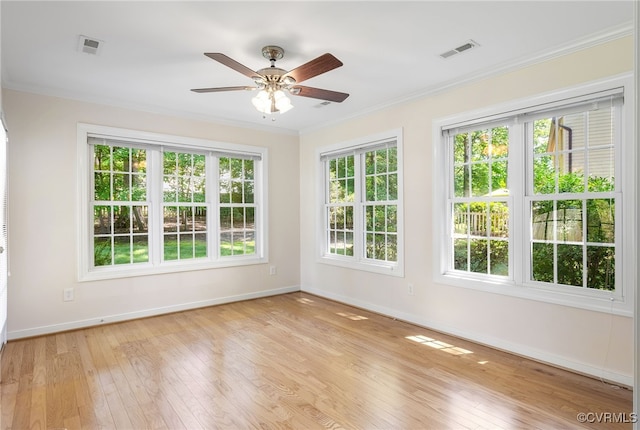 spare room with plenty of natural light, baseboards, light wood-style flooring, and ornamental molding