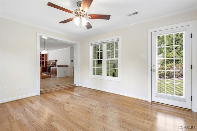empty room featuring a ceiling fan, light wood finished floors, ornamental molding, and baseboards