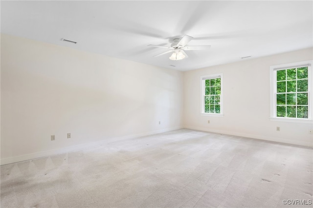spare room featuring a ceiling fan, baseboards, and light colored carpet