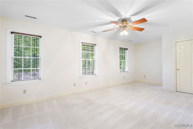 spare room featuring light carpet, baseboards, and a ceiling fan